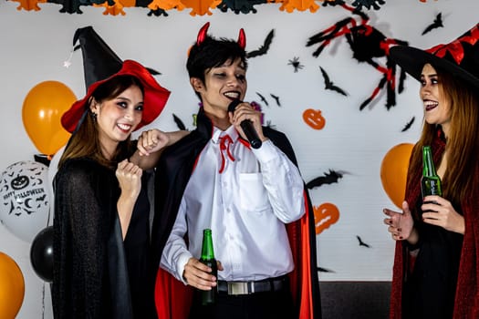 Group of young adult and teenager people celebrating a Halloween party carnival Festival in Halloween costumes drinking alcohol beer singing a song and dancing.