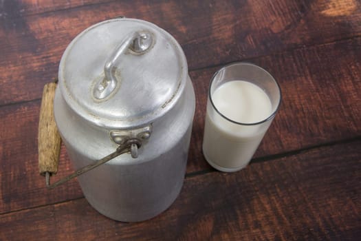 Can and glass of milk on brown wooden background