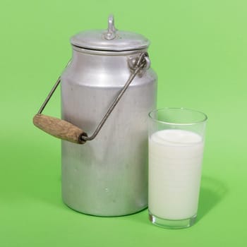 Glass of fresh milk and retro milk canister on green background