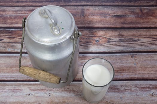 Can and glass of milk on brown wooden background