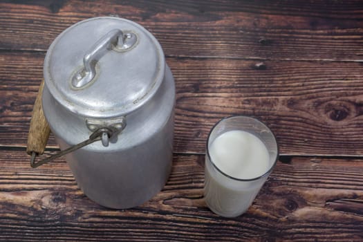 Can and glass of milk on brown wooden background