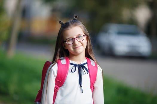 Portrait of smiling schoolgirl with backpack outdoors. Child girl looking at camera. Selective focus.
