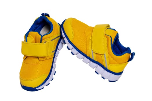 Child shoe fashion. Close-up of a pair of yellow blue child sneaker or sport shoes isolated on a white background. Elegant and trendy shoes for girls. Macro.