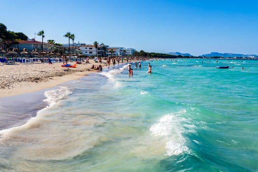 Mallorca, Spain, June 2015 People, tourists enjoying sun holidays on Alcudia beach, view on turquoise sea and sandy beach