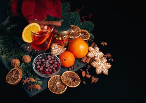 Still life with glasses of mulled wine or fruit tea, Red Poinsettia flowers, fir branch and spices on a dark background. Top view. New year and Christmas table setting. Greeting card.