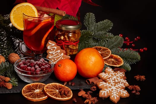 Still life with glasses of mulled wine or fruit tea, Red Poinsettia flowers, fir branch and spices on a dark background. New year and Christmas table setting. Greeting card.