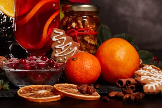Still life with glasses of mulled wine or fruit tea, Red Poinsettia flowers, fir branch and spices on a dark background. New year and Christmas table setting. Greeting card.
