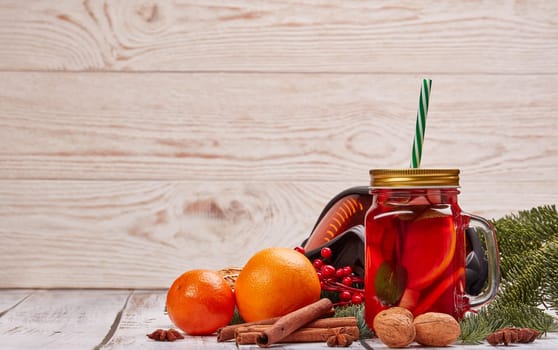 Winter holidays still life with fir tree branch, ski glasses, fruit tea, spices and oranges on a light wooden background with copy space. New Year and Christmas. Winter vacation.