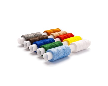 Set of multi-colored spools of cotton thread lying diagonally isolated with real shadow. Side view