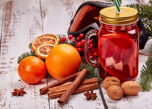 Winter holidays still life with fir tree branch, ski glasses, fruit tea, spices and oranges on a light wooden background. New Year and Christmas. Winter vacation.