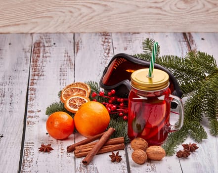 Winter holidays still life with fir tree branch, ski glasses, fruit tea, spices and oranges on a light wooden background with copy space. New Year and Christmas. Winter vacation.