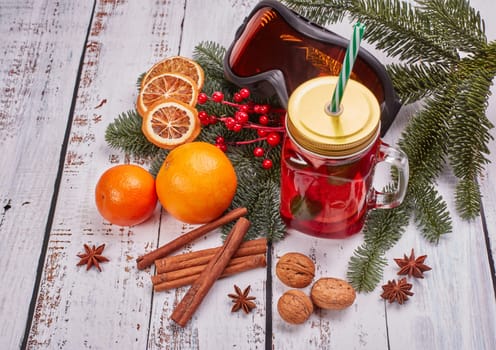 Winter holidays still life with fir tree branch, ski glasses, fruit tea, spices and oranges on a light wooden background. Top view. New Year and Christmas. Winter vacation.