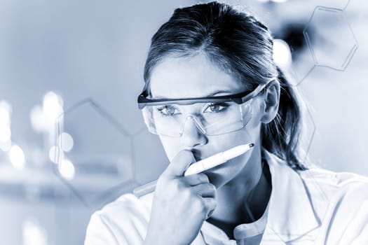 Portrait of a confident female health care expert in life science laboratory writing structural chemical formula on a glass board. Healthcare and modern life science concept. Blue toned image.