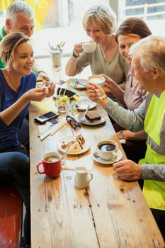 A group of five people taking a break from city cleaning and having coffee and cake.