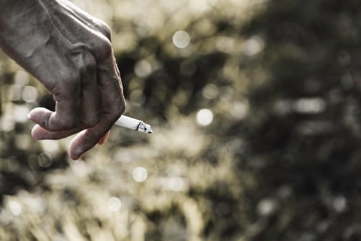 Hand holding a cigarette. A man smoking a cigarette and copy space for insert text.