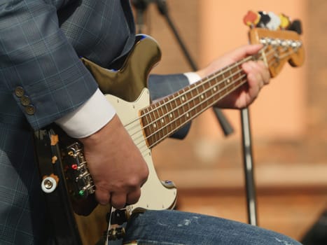 music, hand musician playing bass guitar close-up