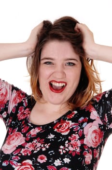 A young screaming woman in a close up image with her mouths open.and her hands in her blond hair, isolated for white background.