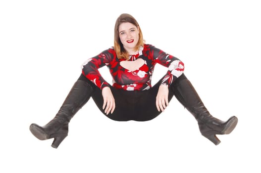 A beautiful young woman in a colorful blouse and black tights and.boots sitting on the floor, resting, isolated for white background.