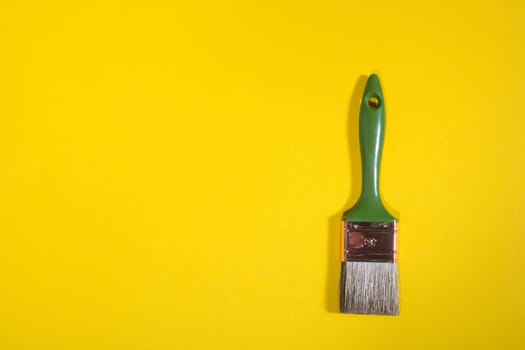 Green Paint brush on yellow background with copy space