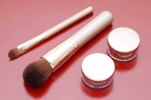 closeup of make up powder and brush on red background
