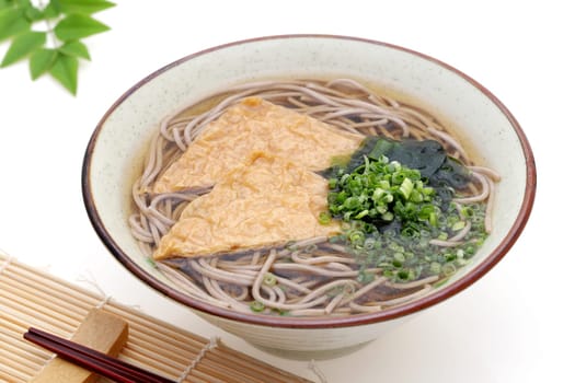 Japanese Kitune soba noodles in a ceramic bowl on white background
