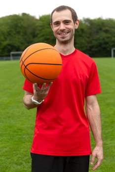 Young friendly man with basketball in soutdoor sports area