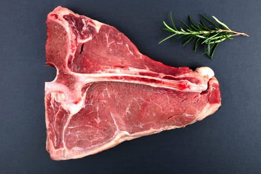 Raw T Bone Steak with Rosemary isolated on dark background