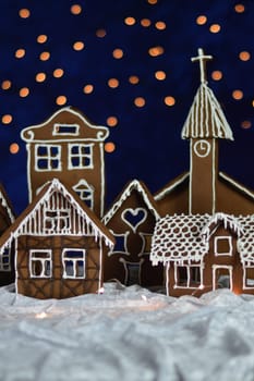 home made gingerbread town with church and bokeh sky out of blue velvet and christmas lights as advent decoration for the family