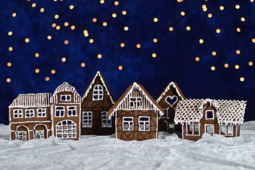 home made gingerbread town and bokeh sky out of blue velvet and christmas lights as advent decoration for the family