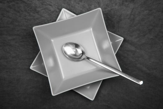 The gray square shaped table set with spoon is served on dark gray background.