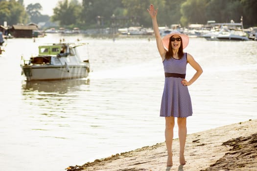Greeting woman is standing on the beach and saying hello, welcome summer.