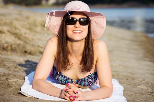 The attractive smiling woman is enjoying and sunbathing on the beach at summer.