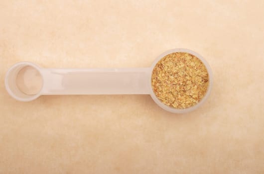 Wheat germs in measuring spoon on brown background