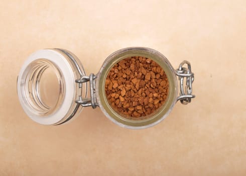 Instant Coffee in open jar on brown background