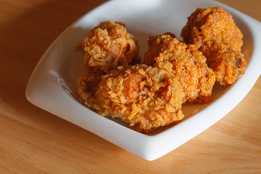 Fresh fried chicken on a white plate set on a wood table background