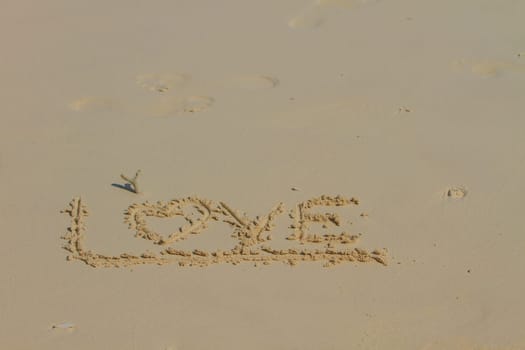 Word LOVE on sand, Drawing love word on beach