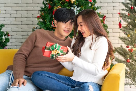 beautiful happy asian girl opening christmas present gift box from her boyfriend for Christmas holiday season greeting.