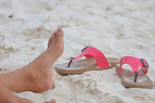 Young girl legs and flip-flop on the sand beach in summer