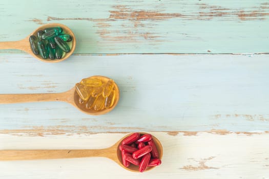 Assorted pharmaceutical medicine pills, tablets and capsules on wooden spoons on vintage wooden table for medicine background