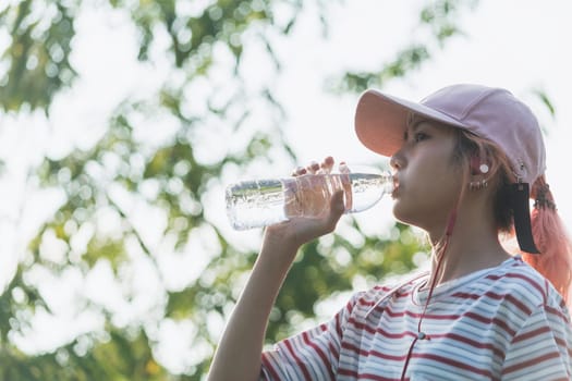 Close up of a woman drinking water from a bottle after exercise. Portrait of a woman drinking a water at outside.