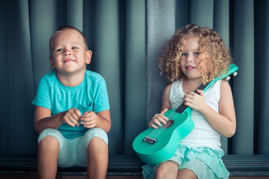 Portrait of a cute kids sitting ouddoor with ukulele