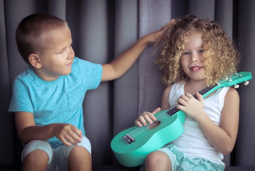 Portrait of a cute kids sitting ouddoor with ukulele