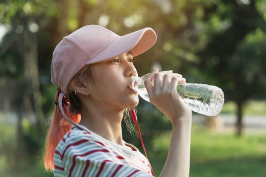 Close up of a woman drinking water from a bottle after exercise. Portrait of a woman drinking a water at outside.