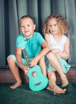 Portrait of a cute kids sitting ouddoor with ukulele