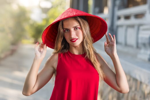 Fashion portrait of a beautiful woman in red conical hat outdoor