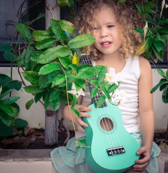 Portrait of a cute girl sitting ouddoor with ukulele