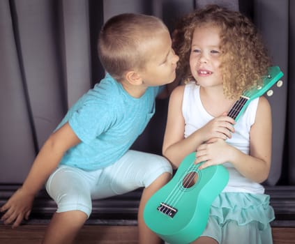 Portrait of a cute kids sitting ouddoor with ukulele