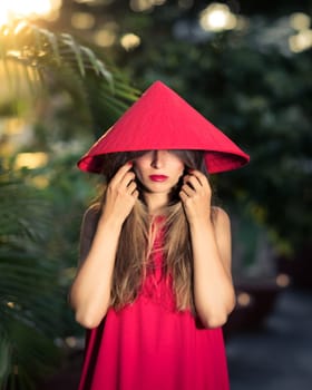 Fashion portrait of a beautiful woman in red conical hat outdoor