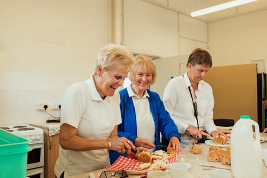 Three senior women having fun making scones, with one smiling at the camera.