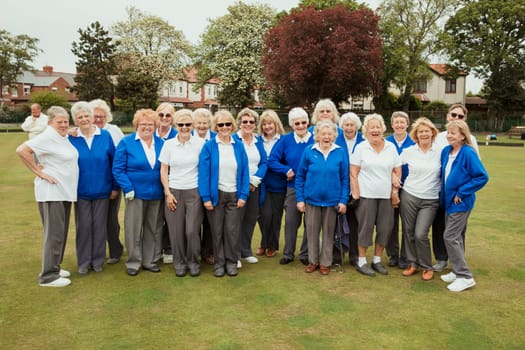 A front view shot of a community of senior women smiling at a bowling green.